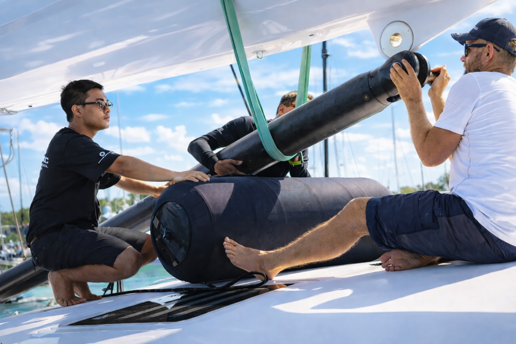 Crew installing a Navtec hydraulic ram on a sailing yacht as part of standing rigging inspection and maintenance.