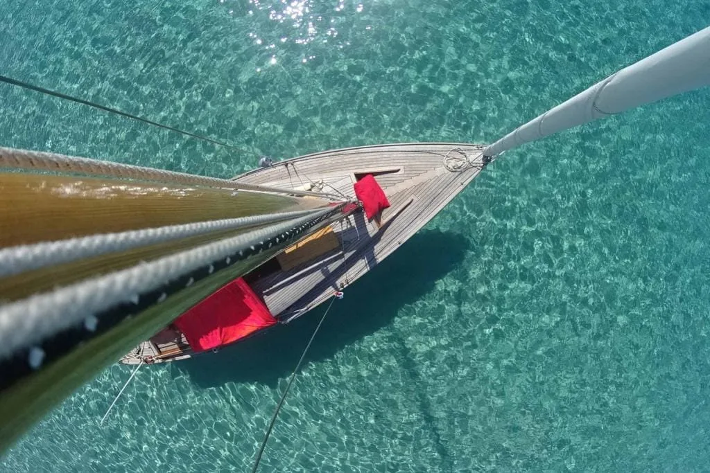 A yacht on an azure sea viewed from the top of the mast above