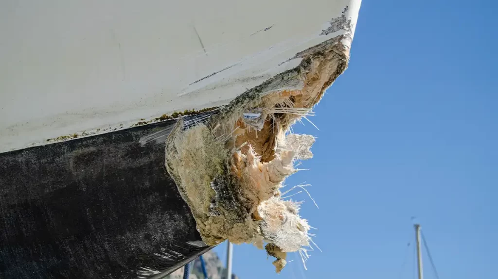 Yacht Refit Fibreglass - The end of a hull is seen to be damaged and fibreglass is exposed