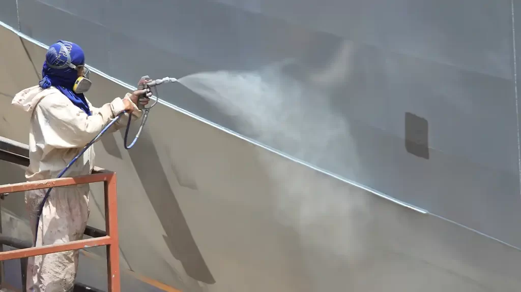 Hull Painting technician is spray the hull of a superyacht with white paint