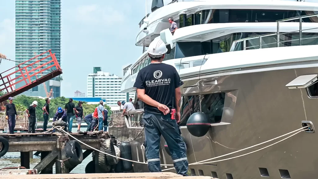 Clearvac Engineering Asia technician supervising a superyacht alongside the pier at Bangkok Dock, Thailand, during refit operations. The image shows skilled marine engineers working on a luxury yacht as part of professional superyacht maintenance and refit services featured in the blog The Best Superyacht Refit Companies in the World