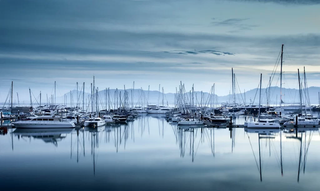Yachts moored at Phuket Yacht Haven Marina with calm water reflections and marina berths in northern Phuket, Thailand