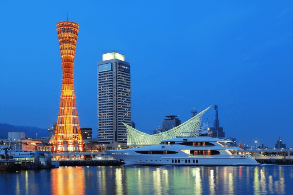 Luxury superyacht in Kobe Harbour with illuminated Kobe Port Tower and modern waterfront architecture at night, Japan