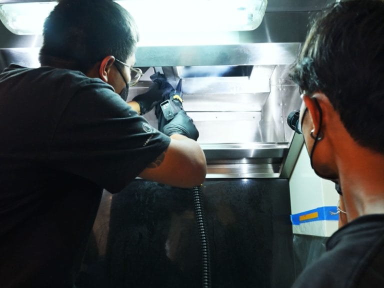 Technicians steam cleaning offshore galley for fire risk removal compliance