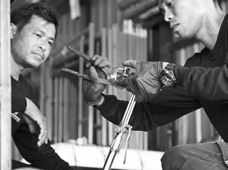 2 marine mechanical engineers are seen adjusting the end of a welding iron