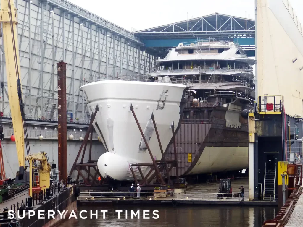 Lürssen superyacht Deep Blue under construction in dry dock, showing the bow section being positioned for attachment to the main hull at the Bremen shipyard.