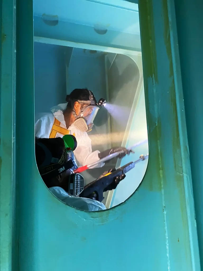 Clearvac technician performing confined space tank cleaning with protective suit, respirator, and specialized equipment onboard vessel