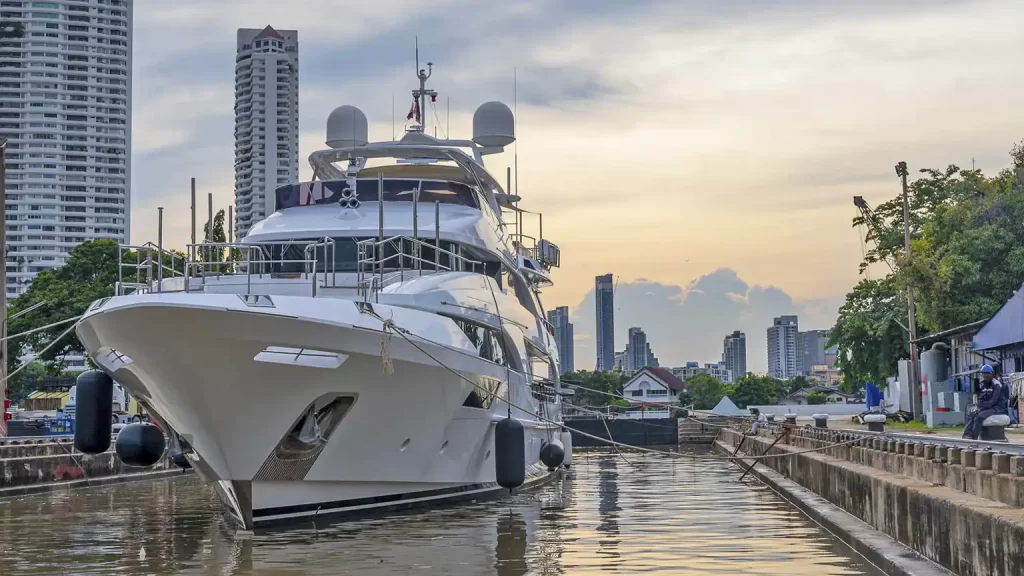 Superyacht undergoing refit at Bangkok Dry Dock with Clearvac Engineering Asia. The white motor yacht is moored in the dockyard with Bangkok’s city skyline behind, showing professional yacht repair, mechanical service, and refit facilities for luxury vessels in Thailand.